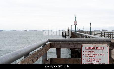 Containerschiffe warten auf den Zugang zum Hafen von Los Angeles, wie man vom Seal Beach Pier in Seal Beach, Kalifornien, USA, aus sieht Stockfoto