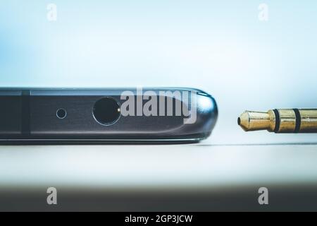 Anschluss der 3,5-mm-Audiobuchse an ein schwarzes Mobiltelefon. Stockfoto