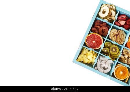 Box mit getrockneten Früchten Chips isoliert auf weiß, Draufsicht. Ananas, Kokosnuss, Kiwi, Erdbeere, Orange, Birne, Apfel, Banane natürliche Chips Stockfoto