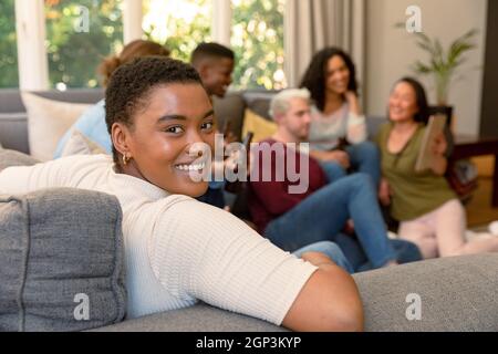 Glückliche afroamerikanische Frau, die Spaß mit verschiedenen Gruppen von weiblichen und männlichen Freunden zu Hause hat Stockfoto