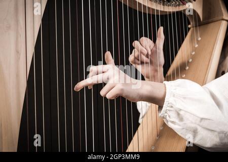 Hände spielen Holzharfe auf schwarzem Hintergrund Stockfoto