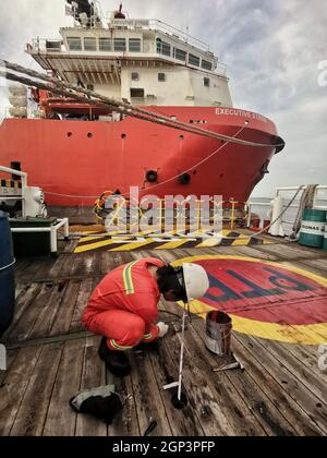 Motorseebesatzung sondiert Heizöl während der Bunkerung am Hafen mit kompletter persönlicher Schutzausrüstung Stockfoto