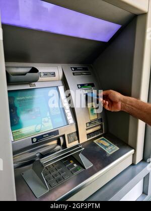 Die Hand des Mannes zieht sein Gehalt vom Geldautomaten ab Stockfoto