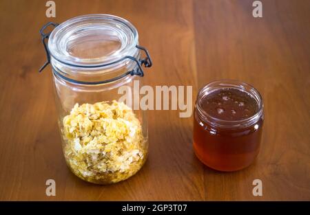 Bienenstock-Produkte: Honig und Bienenwachs in Glasgefäßen auf einem Holztisch Stockfoto