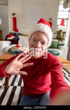 Albino african american Mann trägt weihnachtsmann Hut macht Videoanruf mit weihnachtsschmuck Stockfoto