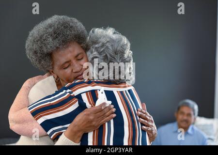 Kaukasische ältere Frau, die eine afroamerikanische Freundin umarmt und sie unterstützt Stockfoto