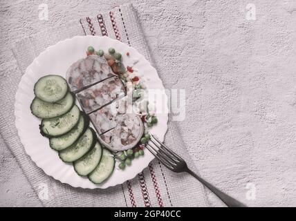 Auf dem Tisch auf einem Teller mit köstlichen Fleisch Vorspeise: Gefüllt mit Fleisch und Speck Schweinefleisch Magen, in Scheiben geschnitten, neben Gemüse und frischen Gurken. Top Vie Stockfoto