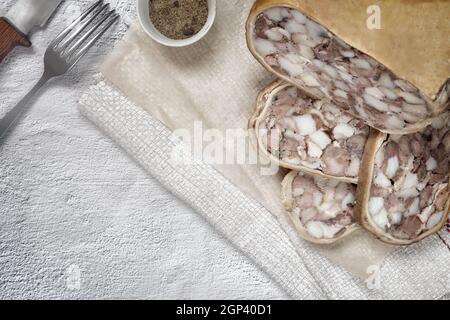 Auf dem Tisch auf einem Teller mit köstlichen Fleisch Vorspeise: Gefüllt mit Fleisch und Speck Schweinefleisch Magen, in Scheiben geschnitten, neben Gemüse und frischen Gurken. Top Vie Stockfoto