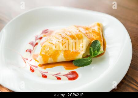 Einige Dessertpfannkuchen mit Erdbeermarmelade, Honig und einer weißen Kugel Eis. Konzept - Menü für ein Café Stockfoto