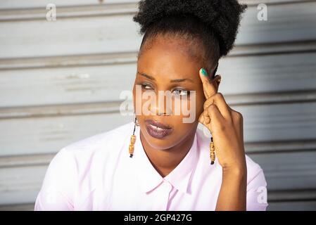 Schöne junge afrikanische Frau sitzt ist nachdenklich Stockfoto