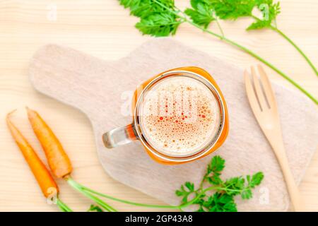 Gläser von Karottensaft mit Karotte Wurzeln auf Holz- Hintergrund. Gläser leckere frische Karottensaft. Karottensaft und Karotten. Selektiver Fokus dept von f Stockfoto