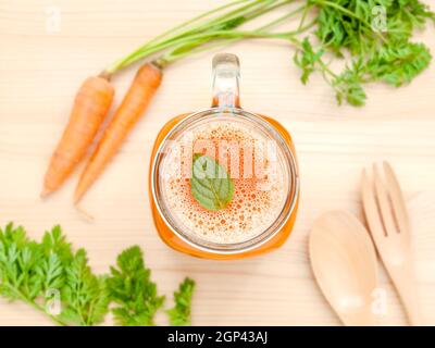 Gläser von Karottensaft mit Karotte Wurzeln auf Holz- Hintergrund. Gläser leckere frische Karottensaft. Karottensaft und Karotten. Selektiver Fokus dept von f Stockfoto