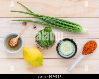 Hausgemachte Hautpflege und Körperpeeling mit natürlichen Inhaltsstoffe Aloe vera, Zitrone, Gurke, Kurkuma Pulver und Honig bis auf Holz- Hintergrund. Stockfoto
