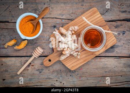 Alternative Pflege - selbstgemachte Peelings curcumin Pulver, Honig und curcumin Wurzeln bis auf alten Holztisch gesetzt. Stockfoto