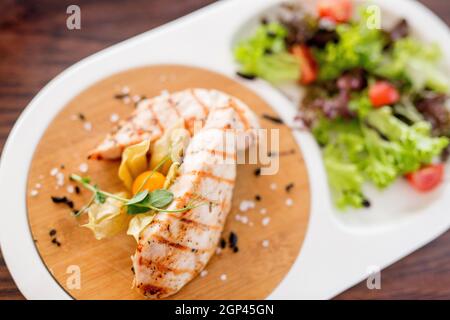 Platte mit Gemüse und Meeresfrüchten. Verschiedene Meeresfrüchte: Gebratene Calamari, gegrillte Garnelen mit Sauce. Gebackenes Fischfilet. Gewürze und Zitrone für Meeresfrüchte. Konz Stockfoto