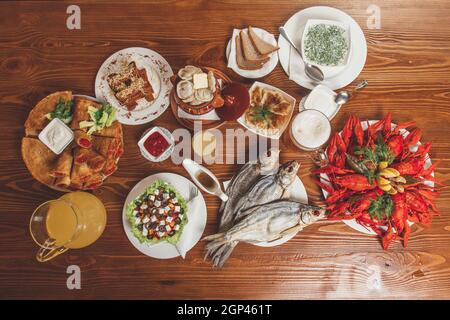 Große Auswahl an Biersnacks: Croutons mit Käse und Knoblauch, getrockneter Fisch, gekochter Krebse, Okroshka, leichtes Bier, Gurken. Konzept - Servieren in einem Be Stockfoto