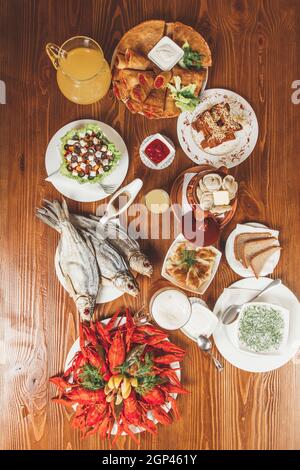 Große Auswahl an Biersnacks: Croutons mit Käse und Knoblauch, getrockneter Fisch, gekochter Krebse, Okroshka, leichtes Bier, Gurken. Konzept - Servieren in einem Be Stockfoto