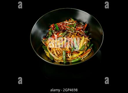 Wok-Nudeln mit Fleischstücken, Hühnchen, Schwein, Kalb. Nahaufnahme, Draufsicht. Concept: Japanische Küche Stockfoto