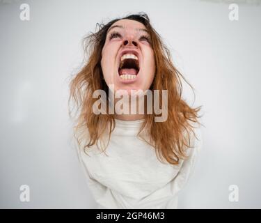 Nahaufnahme Porträt einer verrückten Frau in Zwangsjacke auf weißem Hintergrund. Stockfoto