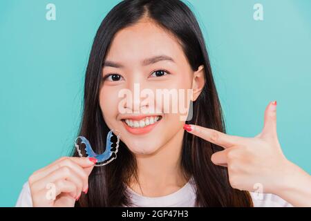 Weibliche halten Zähne Haltewerkzeuge nach abnehmbaren Zahnspangen, Porträt junge asiatische schöne Frau lächelnd zeigt mit Finger Silikon kieferorthodontische retai Stockfoto