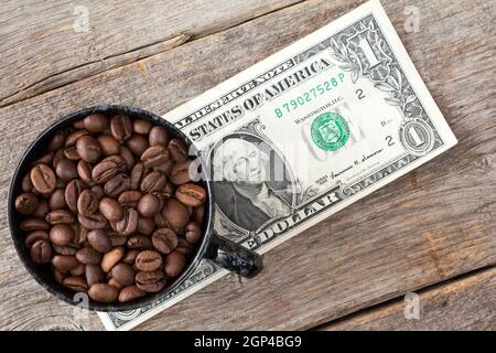 Tasse Kaffee Bohnen auf Dollar Banknote repräsentieren hohe oder niedrige Preise für Kaffee am Aktienmarkt Stockfoto