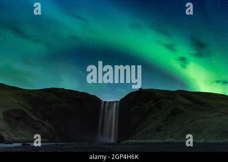 ISLAND. SKOGAFOSS, EIN NORDLICHT ÜBER DEM SKOGAFOSS WASSERFALL. Stockfoto