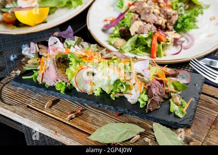 Fleischvorspeise aus Kalbfleisch, Sauce und Gemüse. Grüner Salat zum Dekorieren des Gerichts. Stockfoto