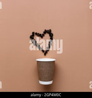 Beige Hintergrund mit Papier Kaffeetasse, Kaffeebohnen Herzform. Hochwertige Fotos Stockfoto