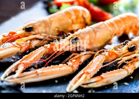 Makro-Nahaufnahme von appetitlich gegrilltem Riesenkrabfisch-Teller mit grünem Salat im Hintergrund. Stockfoto