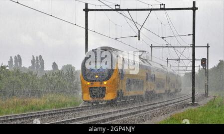 Niederländischer NS-Zug auf einer verregneten Herbstreise in Bunnik (Niederlande) fährt der Zug mit hoher Geschwindigkeit in Richtung Utrecht Hauptbahnhof Stockfoto