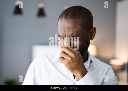 Mann, Der Seine Nase Vor Dem Schlechten Geruch Im Haus Bedeckt Stockfoto