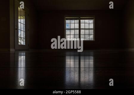 Ein sehr dunkler und fast schwarzer Raum mit dem einzigen Licht, das durch das Fenster und das Türfenster hereinkam Stockfoto