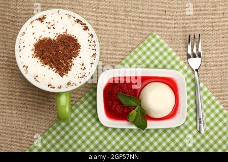 Nahaufnahme serviert Panna Cotta traditionelles italienisches Dessert mit Himbeermarmelade und Tasse Cappuccino-Kaffee, erhöhte Ansicht von oben, direkt darüber Stockfoto