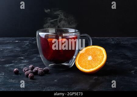 Teetasse mit halbierten Orangen- und gefrorenen Johannisbeeren Stockfoto