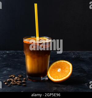 Ein Glas leckeren Kaffee mit Orangensaft auf dunklem Hintergrund Stockfoto