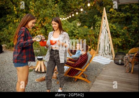 Junge Freunde entspannen sich beim Picknick beim Camping im Wald. Jugend mit Sommerabenteuer auf rv, Camping-Auto auf dem Hintergrund. Zwei Paare Freizeit, travelli Stockfoto