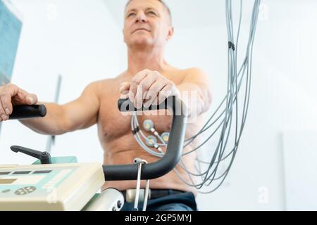 Patient während des Belastungs-EKGs auf einem stationären Fahrrad Stockfoto