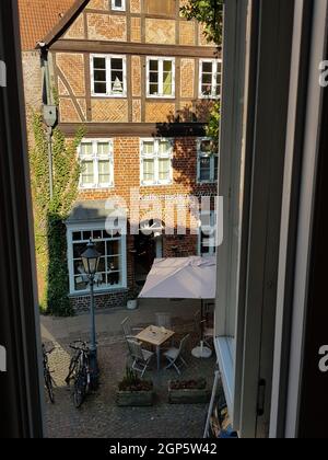 LÜNEBURG, NIEDERSACHSEN, DEUTSCHLAND - 27. JULI 2018: Blick vom Hotelfenster auf einen kleinen Marktplatz und eine Kaffeerösterei in Lüneburg Stockfoto