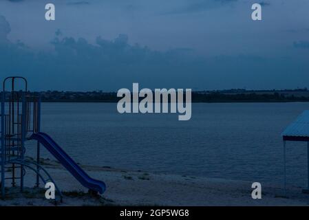 Am Abend Strand blauer Hintergrund, Rutsche und Baldachin auf dem Hintergrund des Flusses. Stockfoto