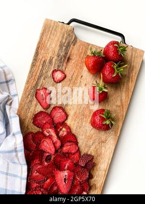 Frische Erdbeeren und getrocknete Erdbeerscheiben auf Holzbrett. Speicherplatz kopieren. Draufsicht Stockfoto