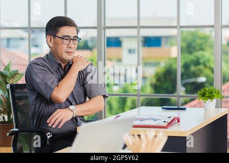 Asian hart Senior Geschäftsmann arbeiten mit Laptop-Computer hat ein Problem mit Schulterschmerzen. Der alte Mann hatte Schmerzen, nachdem er lange Zeit am Schreibtisch gesessen hatte, Hea Stockfoto