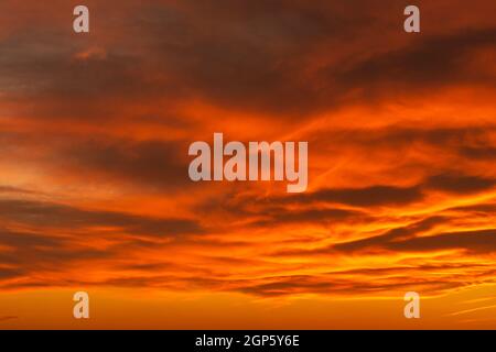 Dramatischer wolkiger Himmel mit kräftigen Farben am frühen Morgen, leuchtende goldene Strahlen durch Wolken am Himmel Stockfoto