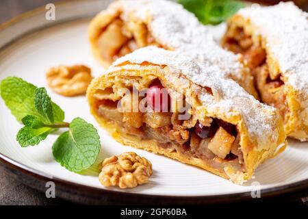 Hausgemachter duftender Strudel mit Äpfeln und Zimt auf einem Teller auf einem hölzernen Hintergrund mit Platz für Text, Stockfoto