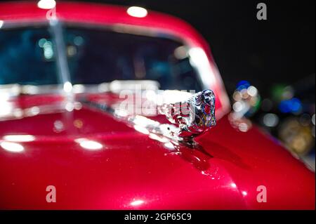 Metallfigur auf der roten Motorhaube eines Oldtimers, Nahaufnahme, selektiver Fokus, weicher Fokus Stockfoto