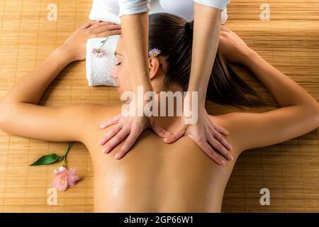 Nahaufnahme der attraktiven Frau, die eine heilende Rückenmassage genießt.Frau, die sich in einer niedrigen Kerzenlichtatmosphäre entspannt. Stockfoto