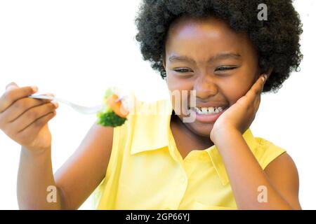 Nahaufnahme Porträt von kleinen afrikanischen Mädchen weigert sich, Gabel mit Gemüse essen.Kind zieht nach oben Nase isoliert auf weißem Hintergrund. Stockfoto