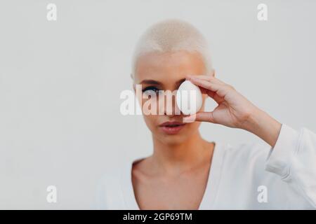 Porträt einer jungen lächelnden, tausendjährigen europäischen Kurzhaarigen Frau, die das Ei in der Hand hält. Schöne glücklich blonde Mädchen im Freien. Stockfoto