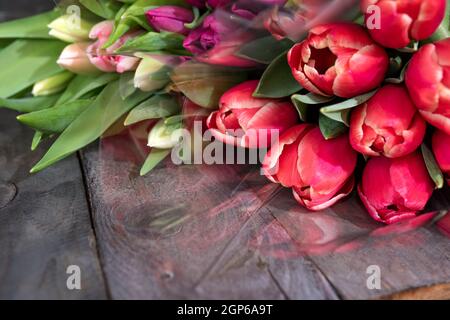 Ein Haufen frischer, farbenfroher Tulpen auf alten Holzbrettern. Frühlingshintergrund für Muttertag und ostern mit Platz für Text. Stockfoto