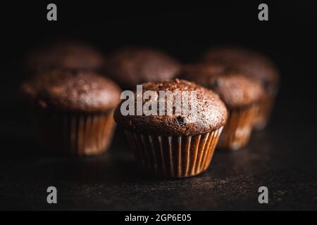 Schokoladen-Muffins. Süße dunkle Cupcakes auf schwarzem Tisch. Stockfoto