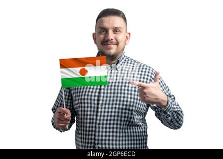 Weißer Kerl hält eine Flagge von Niger und zeigt den Finger der anderen Hand auf die Flagge isoliert auf einem weißen Hintergrund. Stockfoto